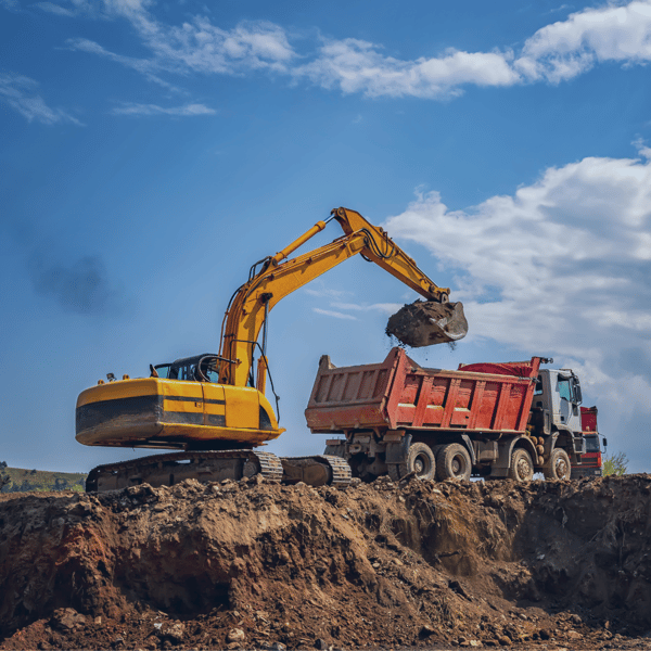 A caving machine loading dirt onto a truck at a construction site